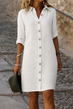 Close-up detail of the roll-tab sleeve on the white linen summer dress, highlighting the button closure.