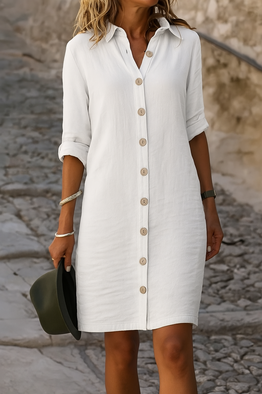 Close-up detail of the roll-tab sleeve on the white linen summer dress, highlighting the button closure.