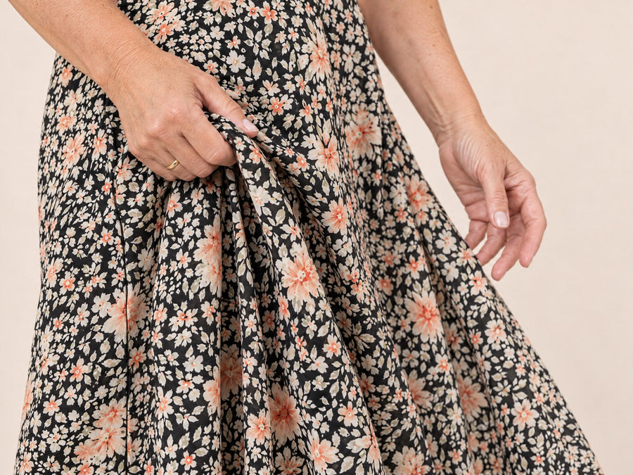 A hand gathering the skirt of an Adeline Wear dress to show the drape
