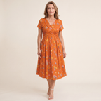 A woman smiling and walking outdoors, demonstrating the comfort and versatility of the stylish floral twist dress.
